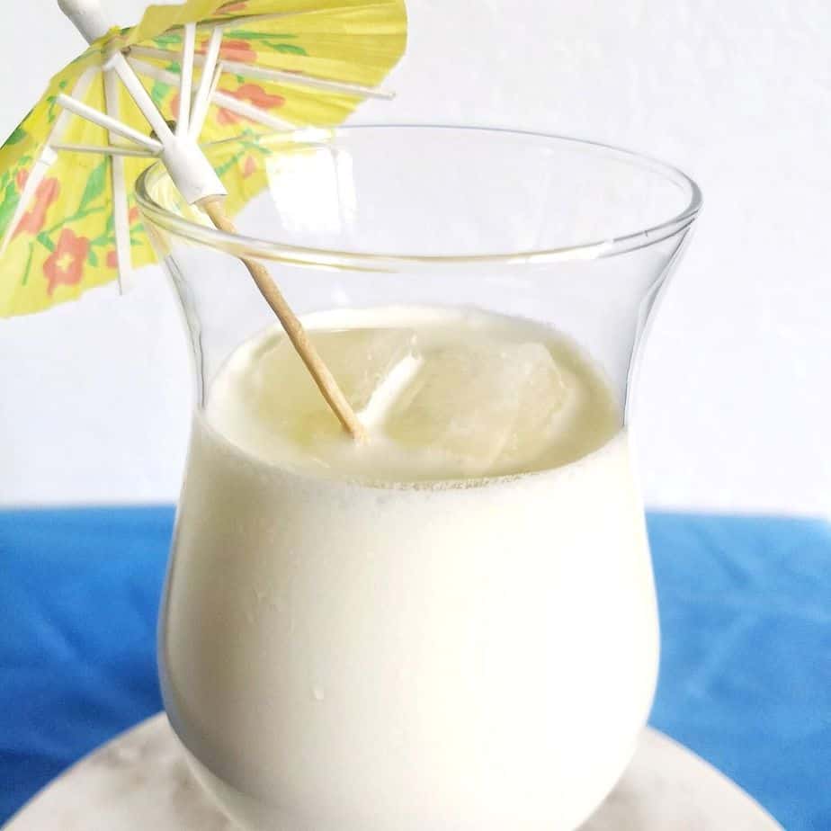 white drink in a glass with a yellow umbrella