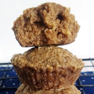 stack of 3 cinnamon muffins w a bite taken out of one of them.