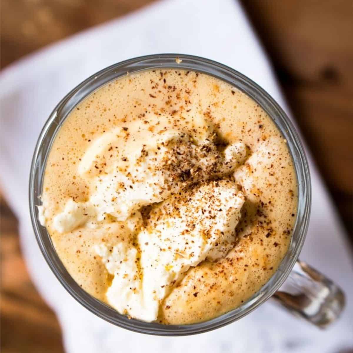 latte with whipped cream on top in a clear glass