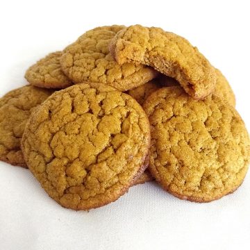 Pile of pumpkin cookies with a bite taken out of one.