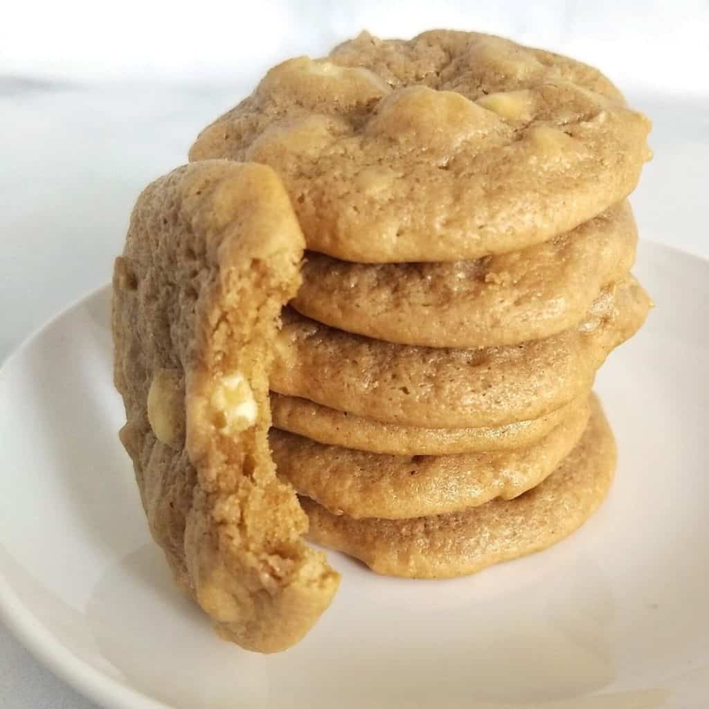 Stack of white chocolate macadamia nut cookies with one next to it bite into.