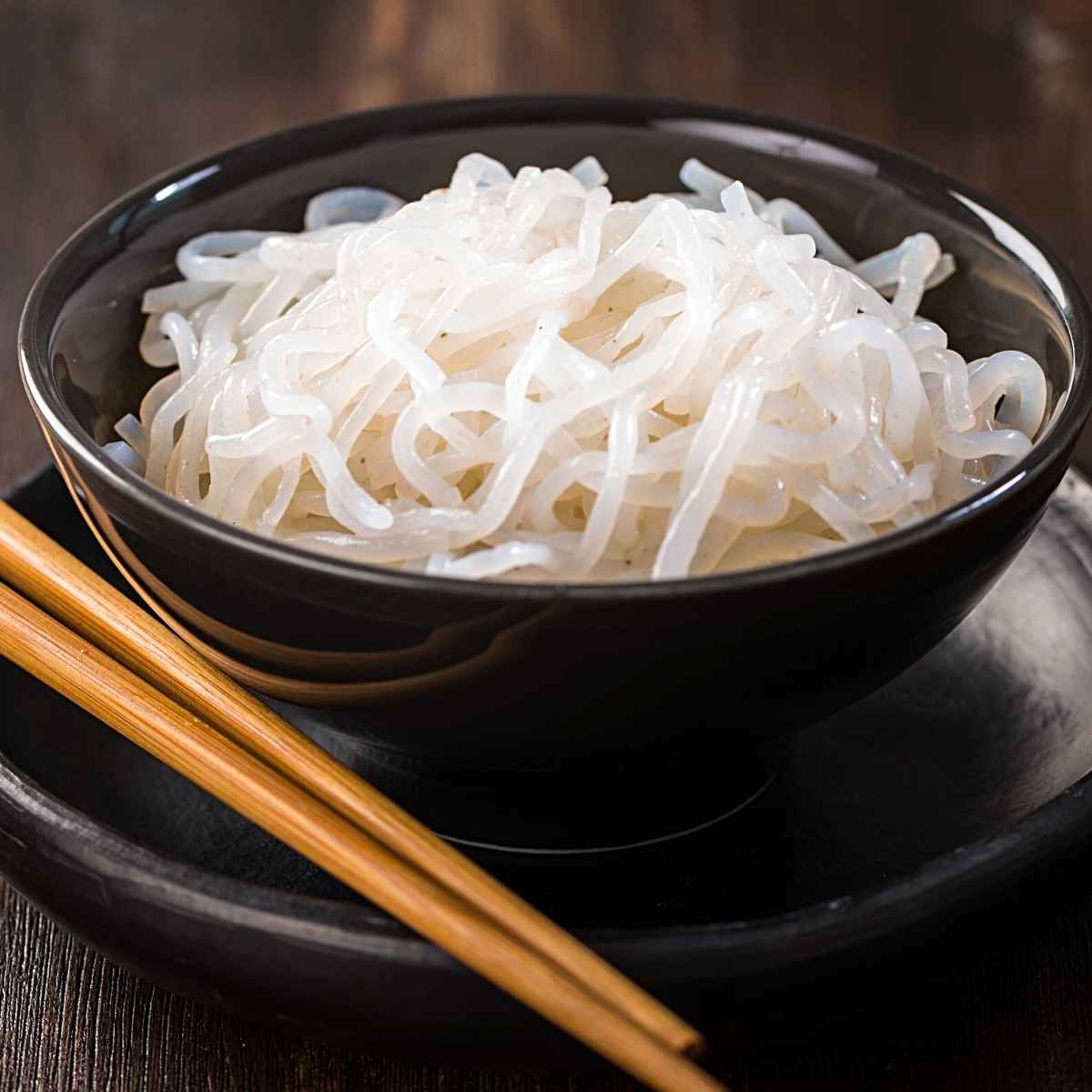 white noodles in a black bowl.