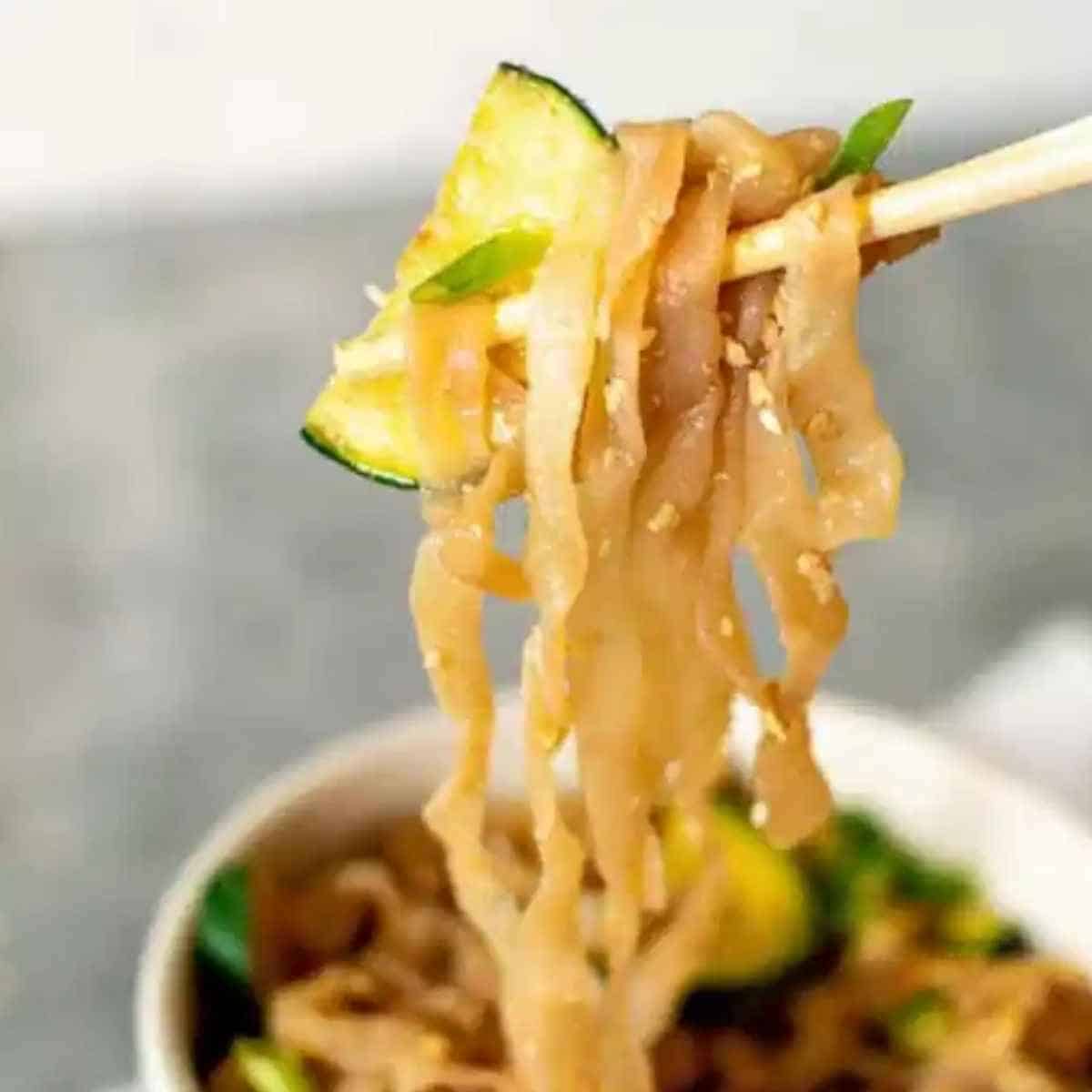 Noodles and zucchini in chop sticks.