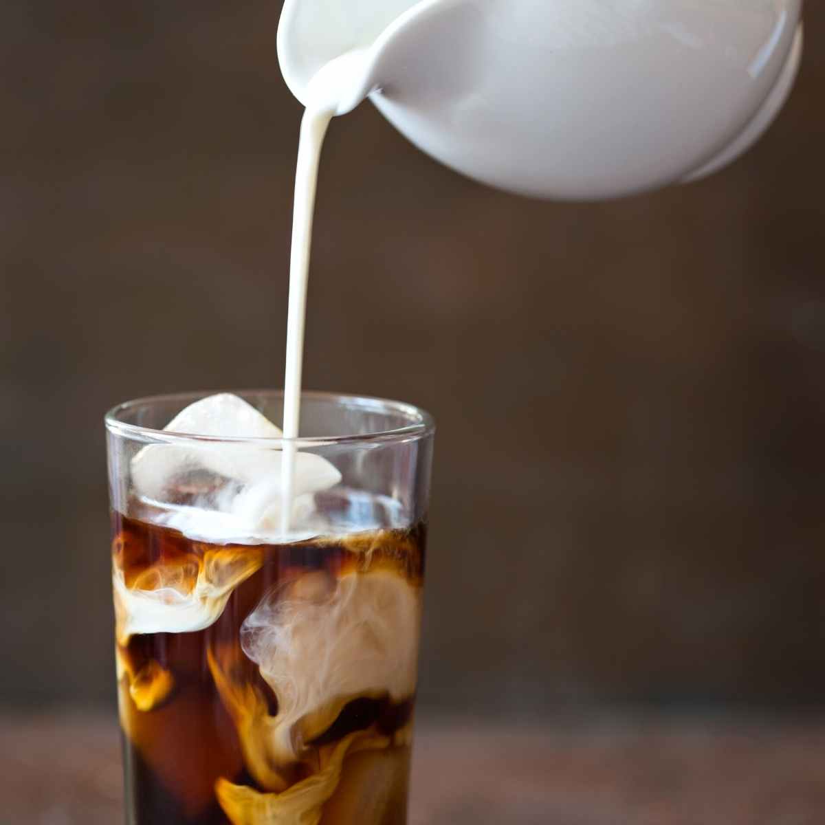 cream being poured into iced coffee