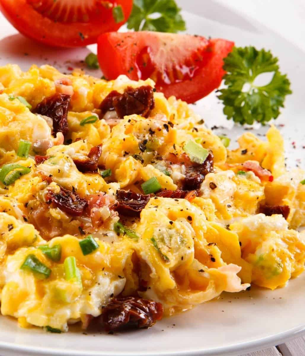 scrambled eggs with tomatoes and cheese and green onions mixed in